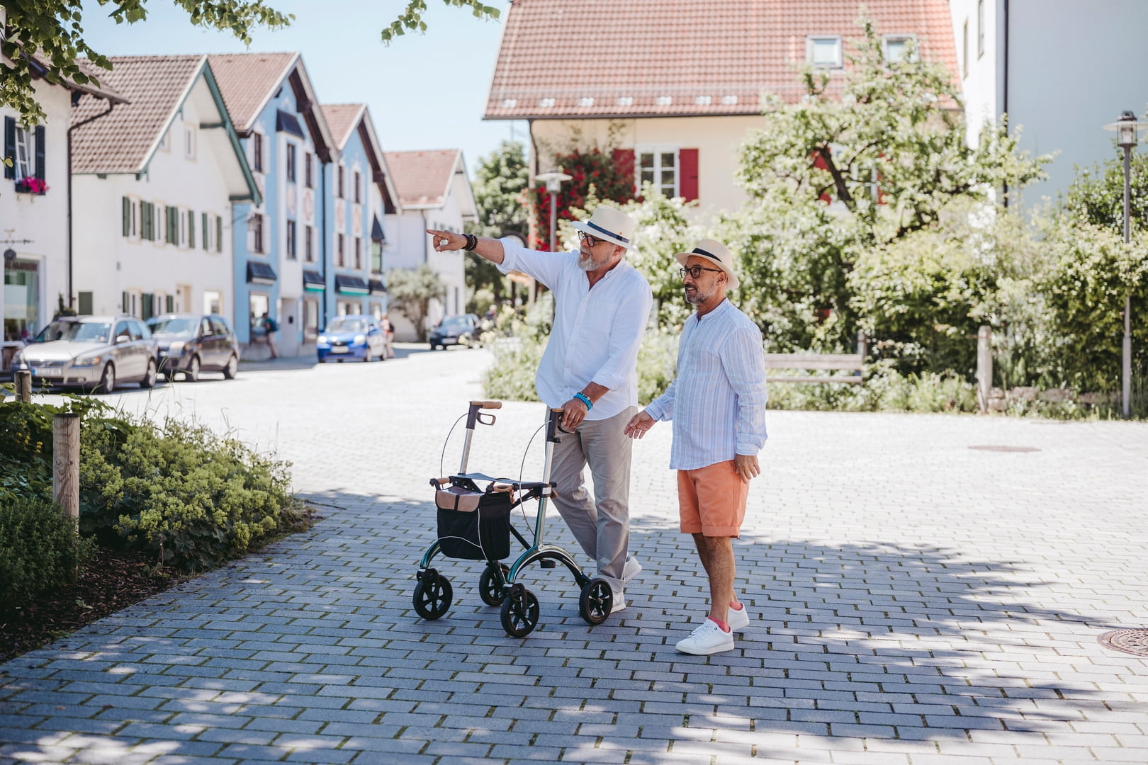 Zwei Männer mit einem Saljol Carbon Rollator auf einem gepflasterten Platz 
